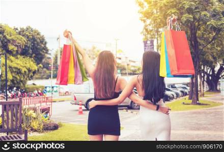 Two beautiful asian woman holding shopping bag at shopping market outdoor.