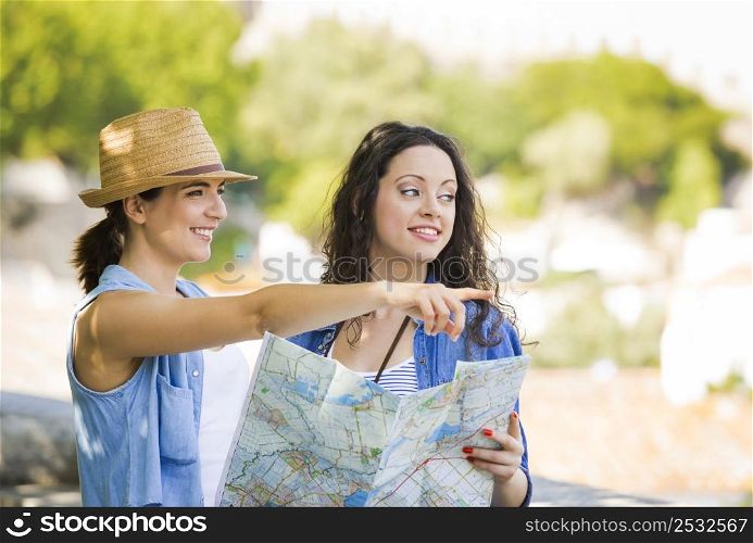 Two beautiful female friends searching a place on the map