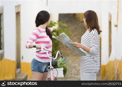 Two beautiful female tourists searching a place on the map