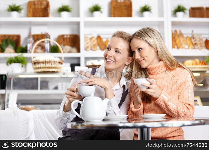 Two beautiful girls discuss something in cafe