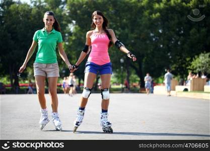Two beautiful girls roller skates in the city park