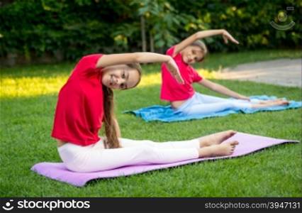 Two beautiful girls stretching and doing yoga at park