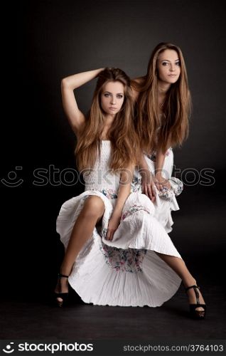Two beautiful girls twins, isolated on the grey background