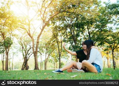 Two beautiful happy young asian women friends having fun together at park and taking a selfie. Happy hipster young asian girls smiling and looking at smartphone. Lifestyle and friendship concepts.