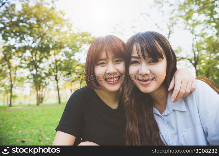 Two beautiful happy young asian women friends having fun together at park and taking a selfie. Happy hipster young asian girls smiling and looking at camera. Lifestyle and friendship concepts.