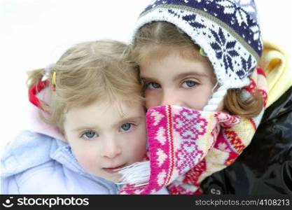 Two beautiful little sisters on the snow with winter wool hat