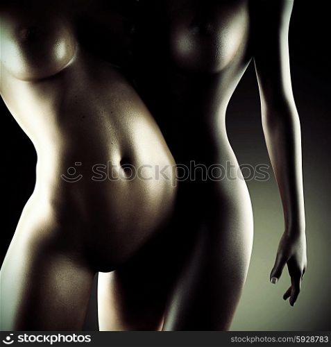 Two beautiful nude sexy lesbian women in erotic foreplay game in dark studio