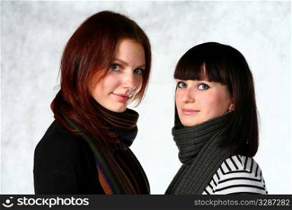 two beautiful redhead and brunette girls with scarf on the gray background