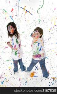Two beautiful teen girls covered in paint with a &acute;caught in the act&acute; expression.