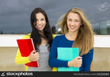 Two beautiful teenage students holding backpacks and smiling