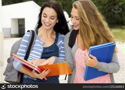 Two beautiful teenage students studying and showing something in the books