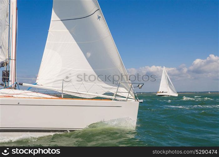 Two beautiful white yachts or sail boats sailing or racing at sea on a bright sunny day