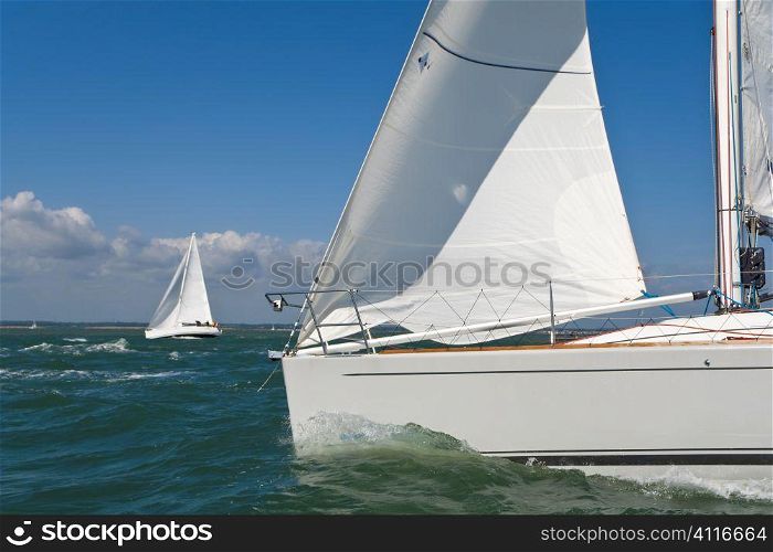 Two beautiful white yachts sailing on a bright sunny day
