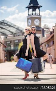 Two beautiful woman posing with shopping bags on street of old city