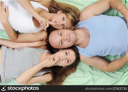 Two beautiful women and man lying on the bed