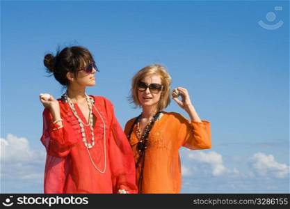 two beautiful women hearing shells on beach