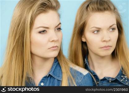 Two beautiful young blonde women having serious face expression. Feminine beauty portrait concept.. Two beautiful young blonde serious women