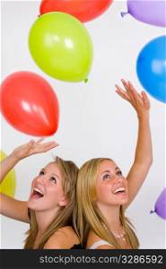 Two beautiful young blonde women in a shower of balloons