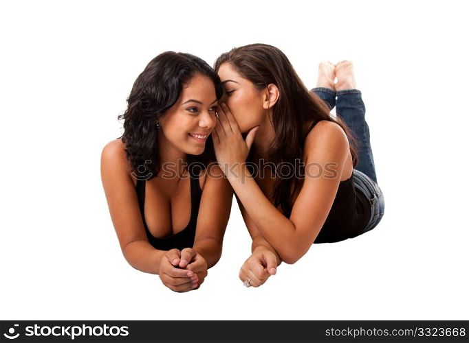 Two beautiful young happy women laying, sharing telling a gossip secret, isolated.
