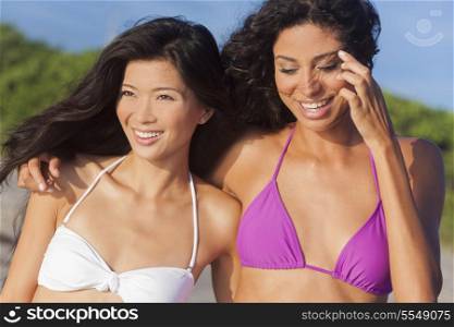 Two beautiful young women one Chinese Asian the other mixed race Hispanic in bikinis having fun at the beach