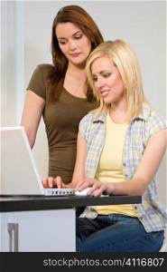 Two beautiful young women using a laptop computer to surf the web.