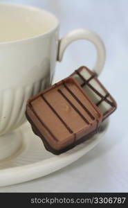 Two belgium chocolate pralines on a tea cup saucer