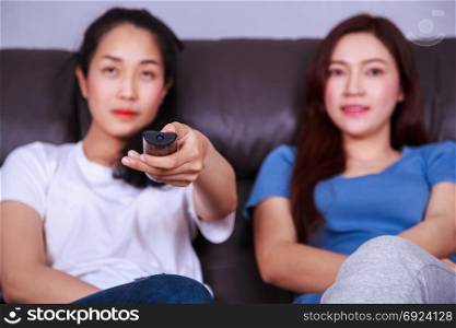two best friends watching tv with remote on sofa in living room at home