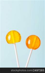 Two big bright tasty lollipops on white sticks blue pastel background vertical with copy space