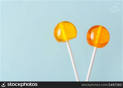Two big bright tasty lollipops on white sticks on blue pastel background with copy space