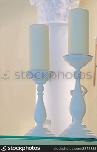 Two big white candles over white candlesticks