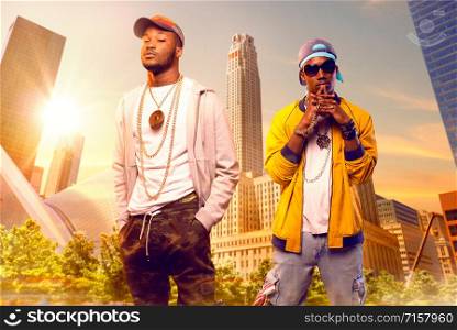 Two black rappers in caps, cityscape on background. Rap performers in city, underground music concert, urban style