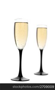 Two black-stemmed wine flutes filled with champagne. Focus on first glass.