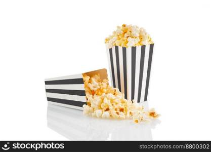 Two black white striped carton buckets with tasty cheese popcorn, isolated on white background. Box with scattering of popcorn grains. Movies, cinema and entertainment concept.