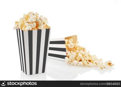 Two black white striped carton buckets with tasty cheese popcorn, isolated on white background. Box with scattering of popcorn grains. Movies, cinema and entertainment concept.