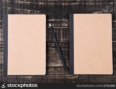 Two blank brown notebooks with black pencil on office desk