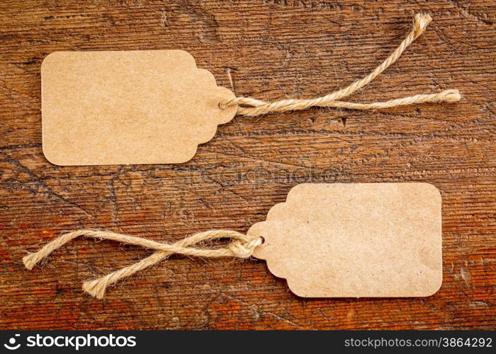 two blank paper price tags with a twine against rustic scratched wood