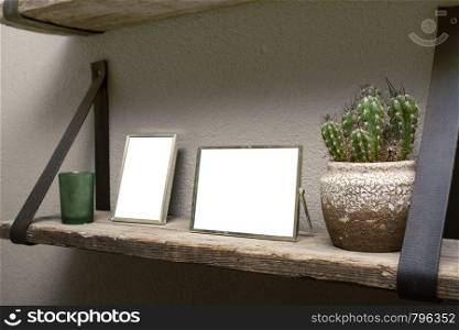Two blank picture frames and cactus decoration on wooden shelf, industrial retro interior design space for text. Two blank picture frames and cactus decoration on wooden shelf, industrial retro interior design