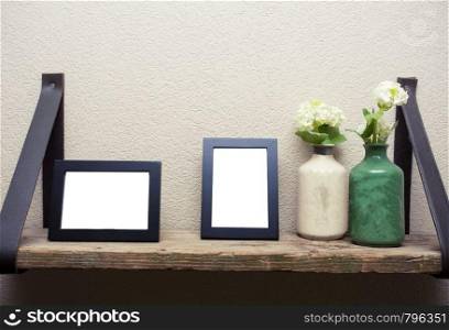 Two blank picture frames with decoration flowers on wood shelf industrial design space for text. Two blank picture frames with decoration flowers on wood shelf industrial design