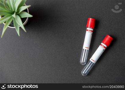Two blood test tubes on black background with blank text area