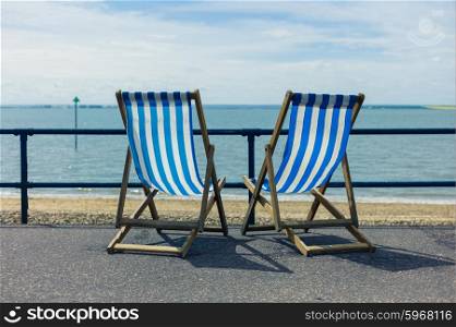 Two blue deck chairs by the seaside on a sunny day