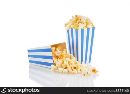 Two blue white striped carton buckets with tasty cheese popcorn, isolated on white background. Box with scattering of popcorn grains. Movies, cinema and entertainment concept.
