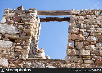 Two boards forming makeshift bridge on old ruins of stone building against blue sky.. Two wooden boards on ruins