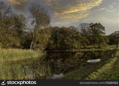 two boats in a pond in the autum forest with red brown and golden colors in national park de veluwe in holland. two boats in a pond with autumn colors