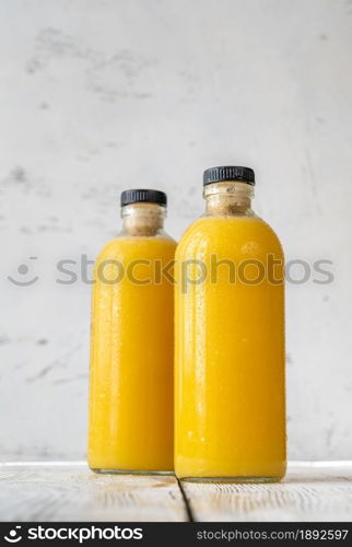 Two bottles of orange juice on the wooden background