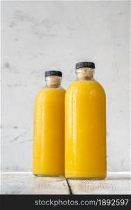 Two bottles of orange juice on the wooden background
