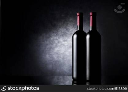 Two bottles of red wine on a black background