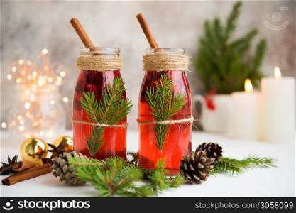 Two bottles of traditional festive mulled wine with berries and spices on a white table with Christmas garlands and Christmas decorations