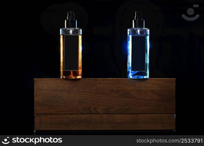 two bottles with yellow and blue liquid. two spray spraying cans on black background on wooden stand. mockup on cans, jars. selective focus. barbershop. tool for hairstyles and beards.. two bottles with yellow and blue liquid. two spray spraying cans on black background on wooden stand. mockup on cans, jars. selective focus. barbershop. tool for hairstyles and beards