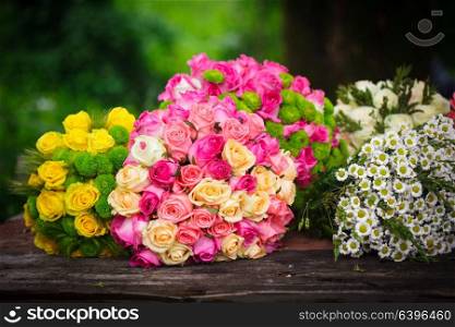 Two bouquets of pink and yellow roses on a wooden florist&rsquo;s table. Florist&rsquo;s table with prepared bouquets
