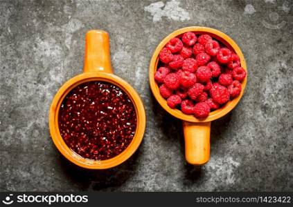 Two bowl with jam and forest berries raspberry. On the stone table.. Two bowl with jam and forest berries raspberry.